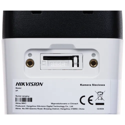 Zbliżenie na tylną część kamery sieciowej Hikvision z widocznym przyciskiem reset i informacjami technicznymi. Na etykiecie znajdują się dane producenta, numer seryjny oraz oznaczenia CE.