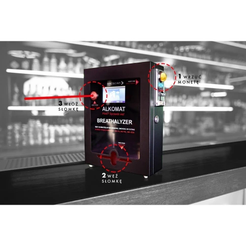 Na zdjęciu znajduje się stacjonarny alkomat BACscan F, umieszczony na ladzie w barze, z widocznymi instrukcjami obsługi oznaczonymi numerami. W tle widać rozmyte półki z butelkami alkoholu.