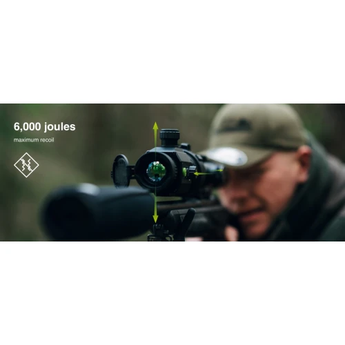 Mężczyzna w czapce celuje z karabinu wyposażonego w celownik termowizyjny w lesie. Na zdjęciu widoczny jest napis "6,000 joules maximum recoil".