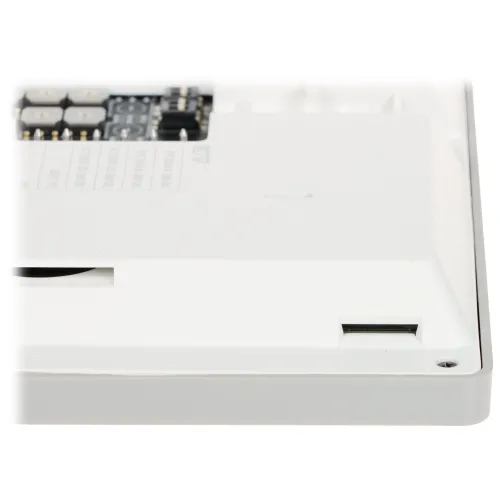 Zdjęcie przedstawia białe urządzenie elektroniczne z widocznym gniazdem na kartę pamięci po prawej stronie. W tle widać fragmenty układów scalonych i komponentów elektronicznych.