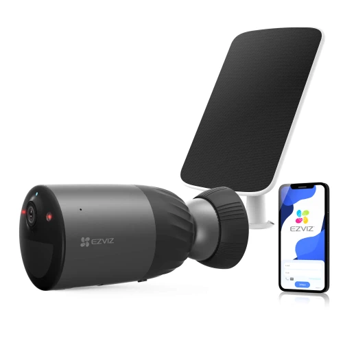 Na zdjęciu znajduje się czarna kamera bezpieczeństwa marki Ezviz oraz panel słoneczny, obok których widoczny jest smartfon z aplikacją Ezviz na ekranie. Kamera i panel są ustawione na białym tle, co podkreśla ich nowoczesny design.