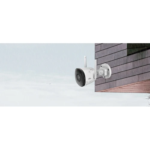 Kamera IP IPC-F22P Wi-Fi Bull jest zamontowana na zewnętrznej ścianie budynku, posiada cylindryczny kształt i dwie anteny dla lepszego zasięgu. Urządzenie jest odporne na warunki atmosferyczne, co czyni je idealnym do monitoringu zewnętrznego.