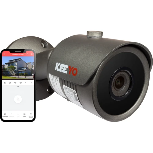 Zdjęcie przedstawia szarą kamerę sieciową IP marki Keeyo z widocznym obiektywem i logo na obudowie. Obok kamery znajduje się smartfon z aplikacją pokazującą podgląd na żywo z kamery.