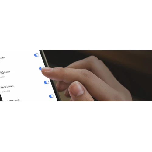 Na zdjęciu widać dłoń obsługującą smartfon z włączonymi przełącznikami na ekranie. Tło jest rozmyte, co skupia uwagę na interakcji z urządzeniem.