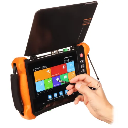 Osoba trzyma rysik i dotyka ekranu wielofunkcyjnego testera CCTV z kolorowym interfejsem. Urządzenie ma pomarańczowe uchwyty i jest wyposażone w osłonę przeciwsłoneczną.