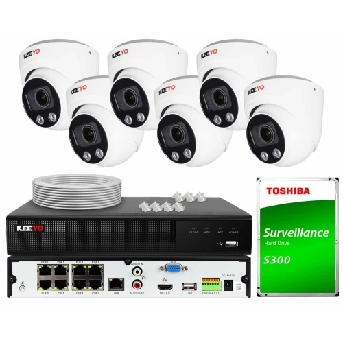 Na zdjęciu znajduje się zestaw do monitoringu, który obejmuje sześć białych kamer kopułkowych, rejestrator wideo oraz dysk twardy Toshiba S300. W tle widoczne są również akcesoria, takie jak kable i złącza.