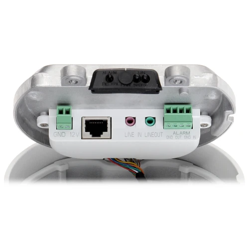 Zdjęcie przedstawia złącza kamery, w tym port Ethernet, złącza audio LINE IN i LINE OUT oraz złącza alarmowe. Widoczne są również oznaczenia GND i 12V, a całość jest zamontowana na metalowej podstawie.